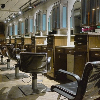 A row of stylist chairs in front of mirrors in a hair salon